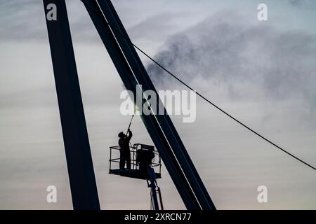 Worker cleans a bridge pier with a high-pressure cleaner on a cherry picker at the Erasmus Bridge over the Nieuwe Maas in Rotterdam, Netherlands Stock Photo