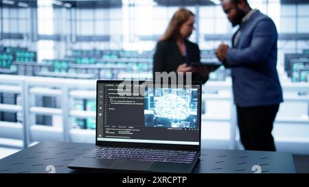 Laptop in data center establishment with artificial intelligence computing simulating human brain. Close up shot of notebook displaying AI machine learning algorithms, camera B Stock Photo