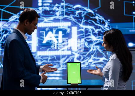 Technician running AI cognitive computing technology on mockup tablet to simulate computerized model. Green screen digital device used by IT employees to do data mining with artificial intelligence Stock Photo