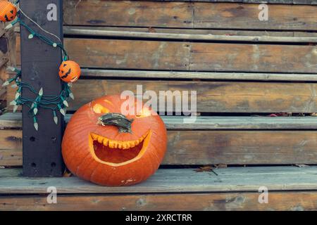 Fall decorations for Halloween holiday. Carved pumpkin on outdoor wooden stairs. Copy space Stock Photo