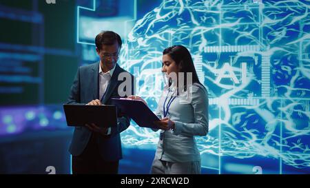 AI researcher and coworker working with artificial intelligence neural networks. Computer scientists collaborating on developing AI system in high tech workspace, camera B Stock Photo