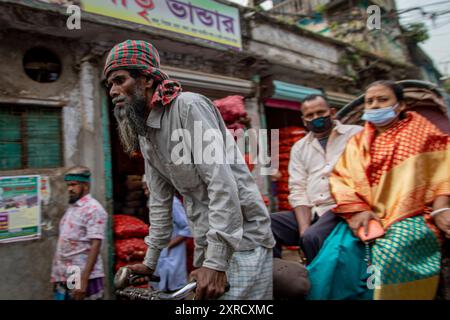 Rickshaw pullers on the streets of Puran Dhaka - Old Dhaka in Bangladesh. The rickshaws are pedal powered tricycles, but used to be pulled by hand, hence 'rickshaw puller'. Nowadays many of the rickshaws are even converted to be powered by electric motor. Stock Photo