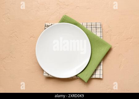 Table setting with plate and napkins on beige background Stock Photo