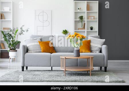 Interior of living room with sofa, table and artificial sunflowers in vase Stock Photo