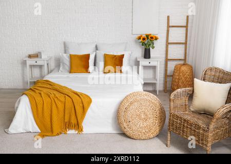 Interior of bedroom with ladder, pouf and artificial sunflowers in vase Stock Photo