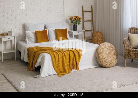 Interior of bedroom with ladder, pouf and artificial sunflowers in vase Stock Photo