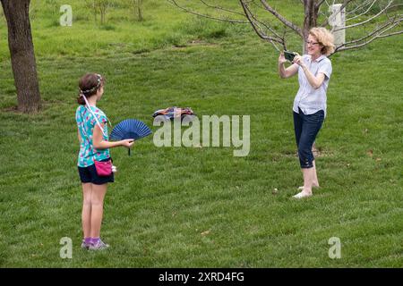 A fifty year old woman takes a photo with her smart phone of her 10 year old girl grandchild. Stock Photo