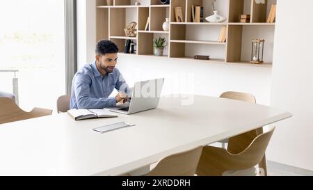 Positive busy young Arab project manager man working at computer Stock Photo