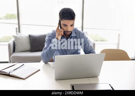 Focused young Arab employee man doing multitasking job Stock Photo