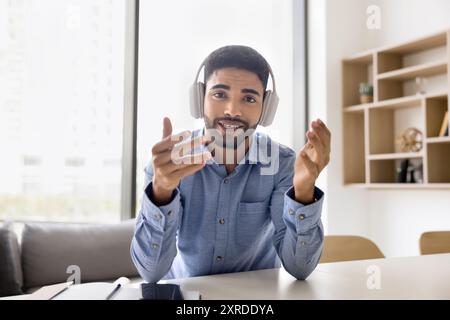 Positive student man in wireless headphones talking on video call Stock Photo