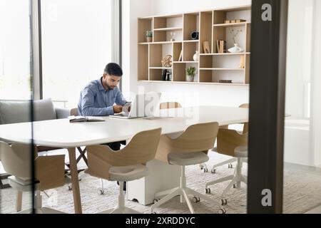 Focused young Arab employee man using digital device Stock Photo