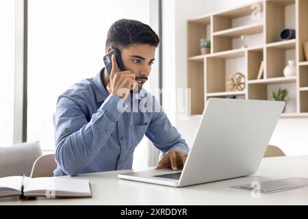 Serious young Arab business man talking on cellphone Stock Photo