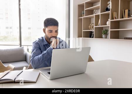 Serious young Arab company manager working at laptop Stock Photo