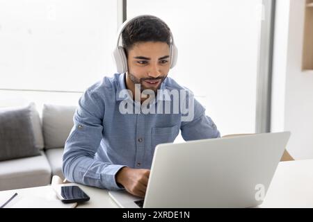 Positive Arab student guy in wireless headphones watching learning webinar Stock Photo