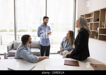 Positive young Arab project manager man talking to colleagues Stock Photo