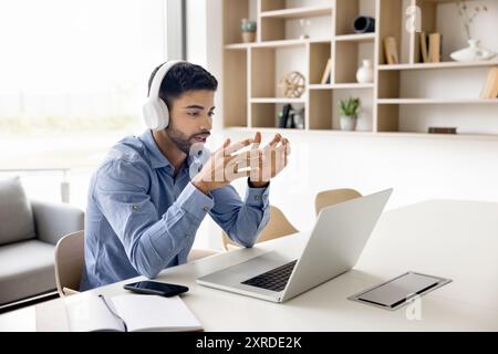 Serious young freelance businessman in headphones talking on video call Stock Photo