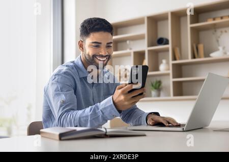 Happy young Arab business man in casual typing on smartphone Stock Photo