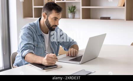Focused handsome Latin business professional man working at laptop Stock Photo