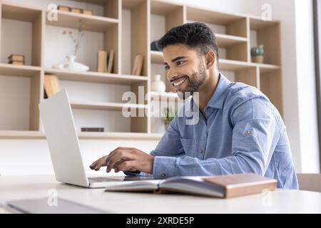 Happy handsome young Arab businessman typing on laptop Stock Photo