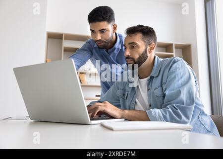 Two serious diverse business project manager men looking at laptop Stock Photo