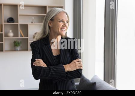 Cheerful mature businesswoman looking at window away Stock Photo