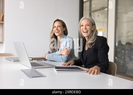 Cheerful female business colleagues sitting at workplace table Stock Photo