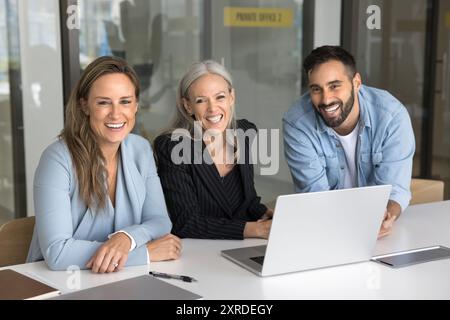 Successful team of three business colleagues sitting at workplace table Stock Photo