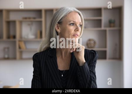 Thoughtful mature businesswoman looking away in office Stock Photo