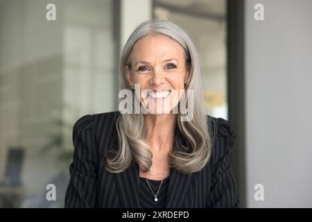 Happy senior executive lady in formal cloth looking at camera Stock Photo