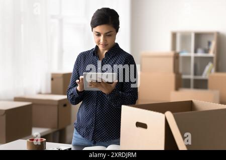 Serious Indian warehouse worker hold digital tablet Stock Photo