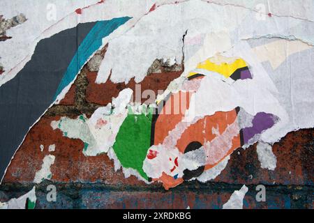 layers of peeling posters on a brick wall, colour and paper texture Stock Photo