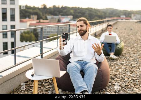 Young professionals working remotely on outdoor rooftop with devices Stock Photo