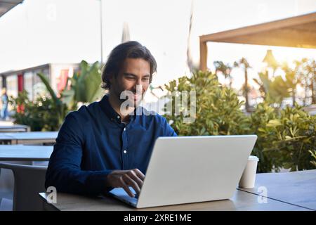 Happy young business man using laptop computer working outdoors with coffee. Stock Photo