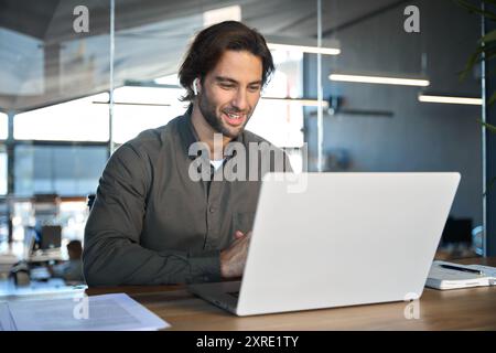 Happy business man wearing earbuds working in office having conference call. Stock Photo
