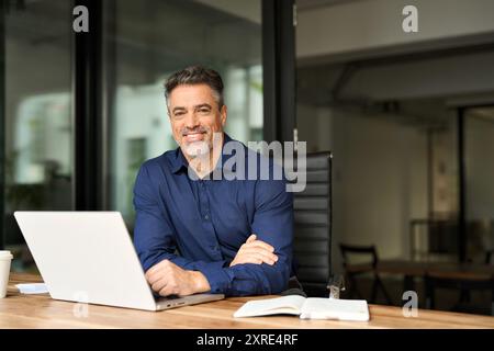 Portrait of happy mature professional business man manager working on laptop. Stock Photo