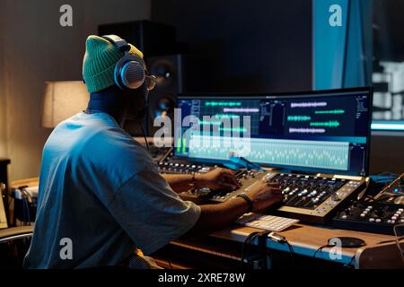 Music producer working on mixing tracks in professional recording studio equipped with modern technology and audio equipment at nighttime Stock Photo