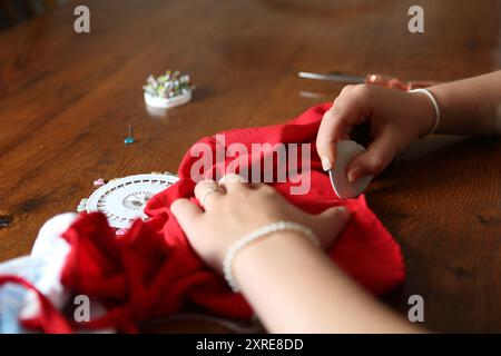 Teenage girl marking textile fabric with chalk - craft skills, sew Stock Photo