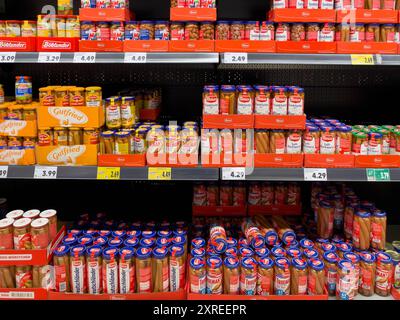 A store shelf with many different types of sausages, including hot dogs. The sausages are in glass jars. Stock Photo