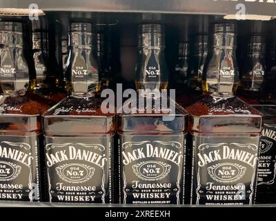 A row of bottles of Jack Daniel's whiskey is lined up on a shelf. All bottles are black and have Whiskey written on the label. Stock Photo