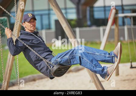 Ringkobing, Denmark, July 2, 2024: Man swinging on a swing Stock Photo