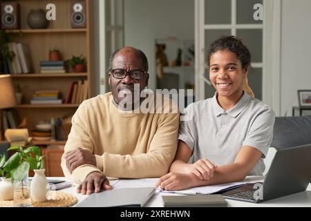 Portrait of Senior Man and Young Woman Smiling at Desk Stock Photo