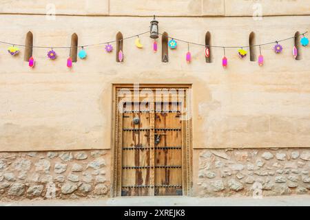 Street with old stone buildings and traditional decorated wooden door, Nizwa, sultanate Oman Stock Photo