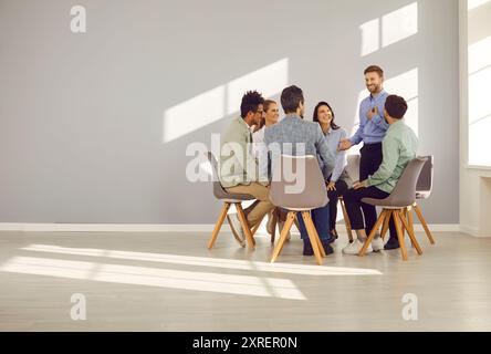 Group of business people sitting on chairs in office in a circle and talking on a meeting. Stock Photo