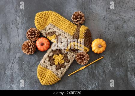Crocheted sleepers on dark grey background with space for text. Handmade knitted baby booties made of wool. Autumn hobby concept. Stock Photo