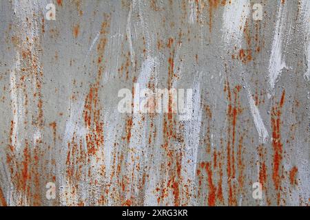 Metallic wall background, texture, colored in grey color with old age rust and white paint streaks. Darkened, rusty surface with strokes of paint Stock Photo