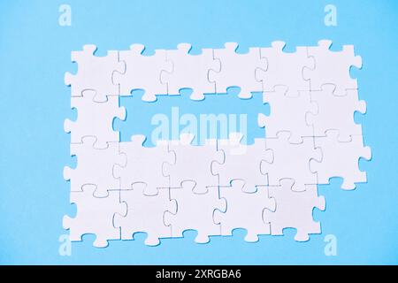 A puzzle with a missing piece is shown on a blue background. Concept of emptiness and incompleteness, as the missing piece represents a gap or void th Stock Photo
