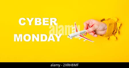 A hand holding a toy airplane with the words Cyber Monday written below it. The image has a playful and festive mood Stock Photo