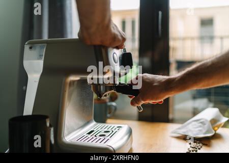 Close-up of hands operating an espresso machine in a modern kitchen setting Stock Photo