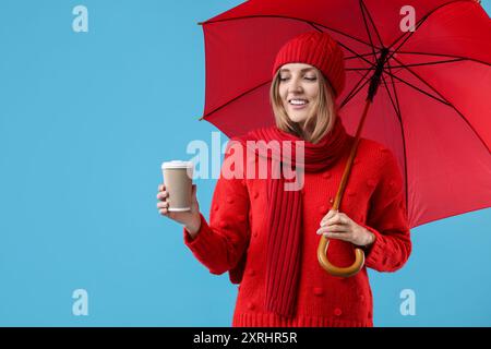 Woman with red umbrella and paper cup on light blue background, space for text Stock Photo