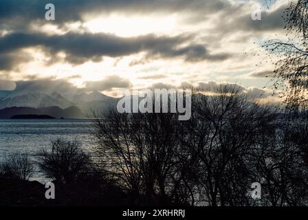 Evening sky with dramatic clouds over mountains, lake and trees. Dramatic sunset over the lake Stock Photo